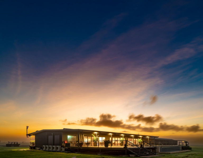 Finniss River Lodge building at sunset with golden sky over open savannah landscape in the Northern Territory.