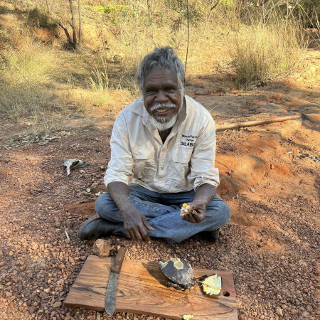 Aboriginal cultural guide seated on Country preparing and explaining bush tucker during a Dalabon Aboriginal Cultural Experience in the Northern Territory.