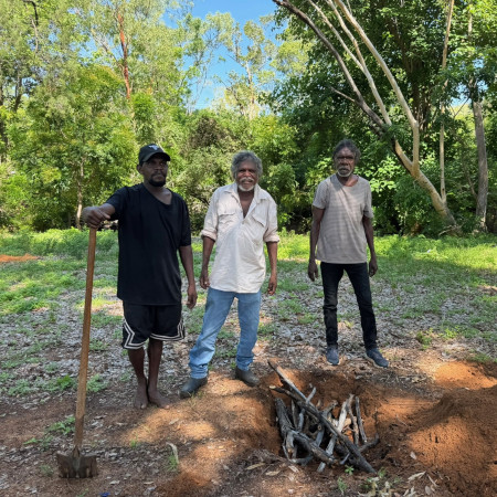 Three Aboriginal men preparing a traditional fire pit for cooking bush tucker as part of a Dalabon Aboriginal Cultural Experience in the Northern Territory.
