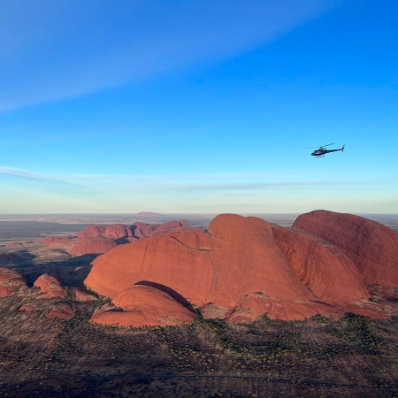 Aerial view of Kata Tjuta and surrounding desert landscape in Central Australia under clear sky.