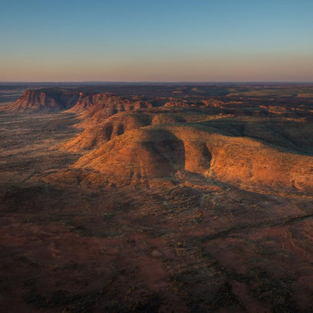 Aerial view rock formations glowing in warm sunset light in the Northern Territory.