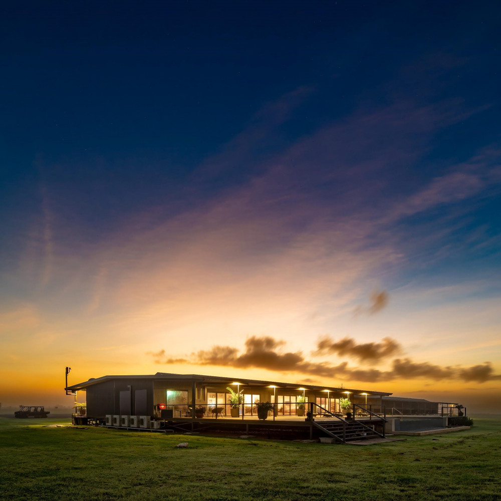 Finniss River Lodge building at sunset with golden sky over open savannah landscape in the Northern Territory.