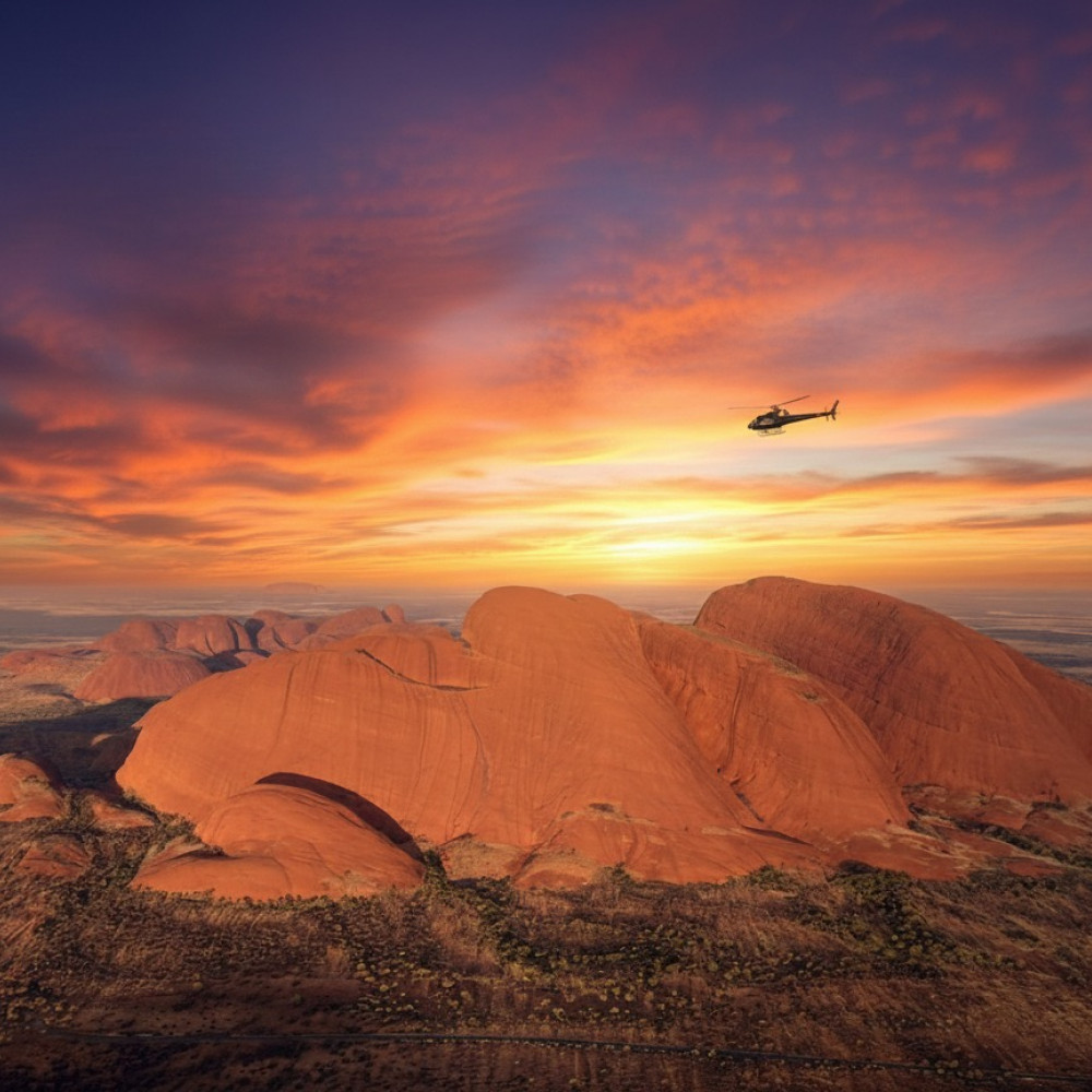 Helicopter hovering above Kata Tjuta at sunset in Central Australia.