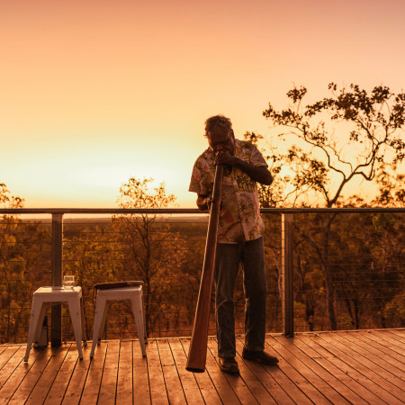 Person playing digeridoo with sunset in background 